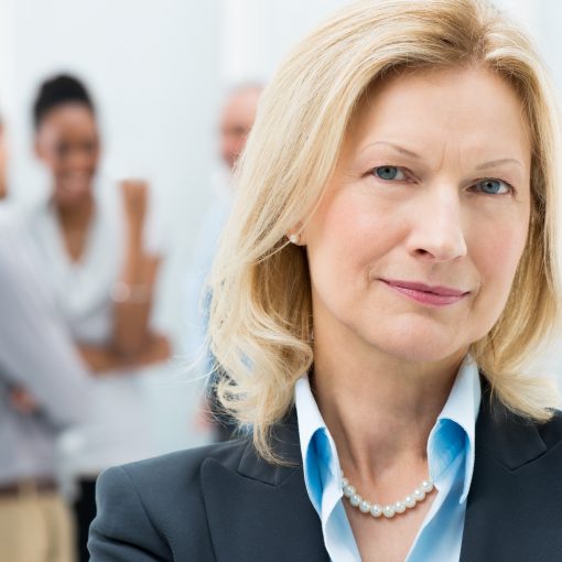 Team of office workers standing and talking with woman in front, facing camera